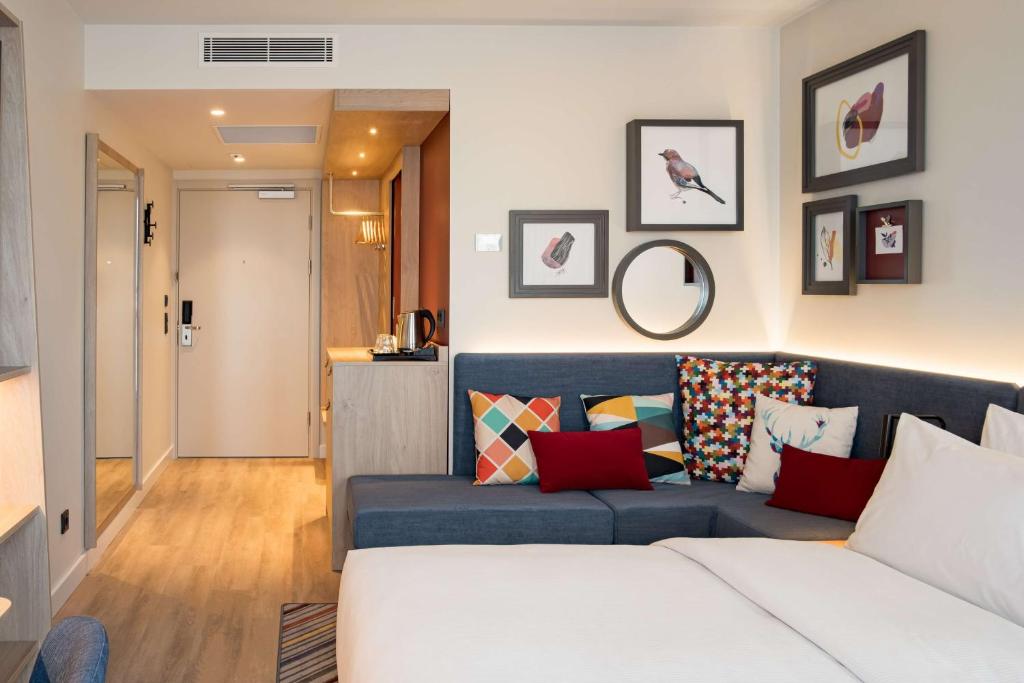 a living room with a blue couch with colorful pillows at Hampton by Hilton Riga Airport in Riga