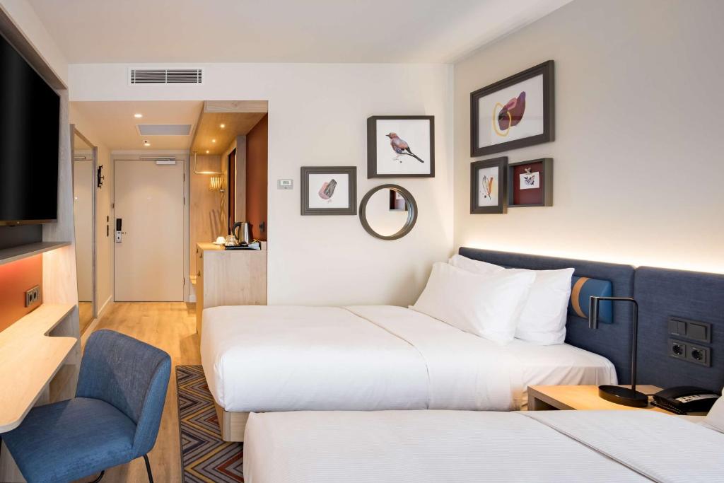 a hotel room with two beds and a chair at Hampton by Hilton Riga Airport in Riga