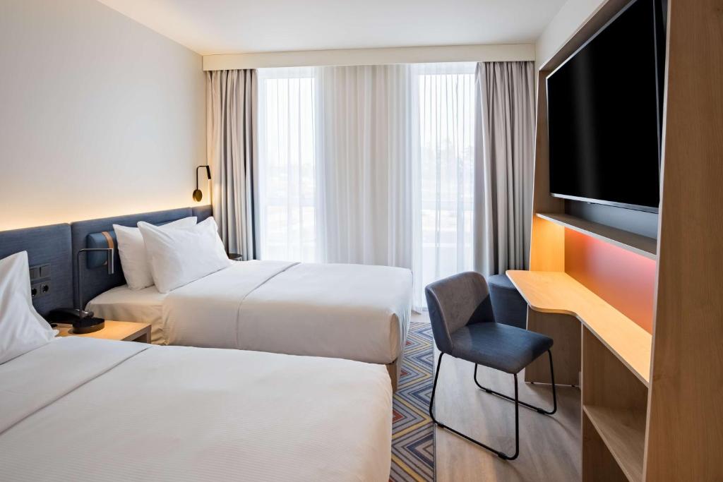 a hotel room with two beds and a flat screen tv at Hampton by Hilton Riga Airport in Riga