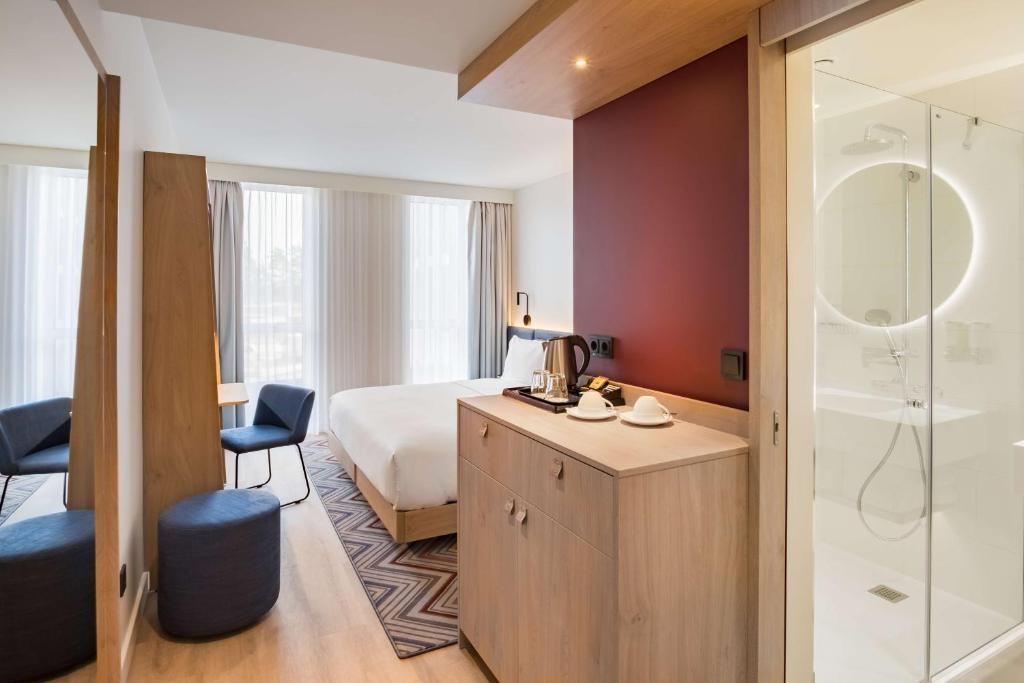 a hotel room with a bed and a shower at Hampton by Hilton Riga Airport in Riga