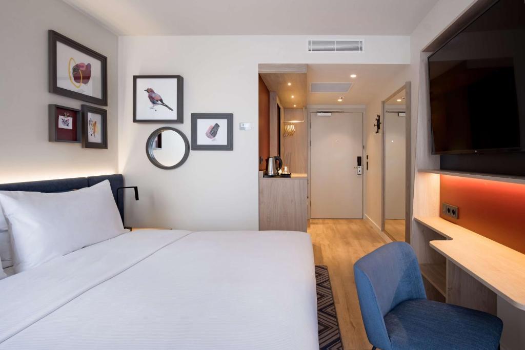a bedroom with a white bed and a blue chair at Hampton by Hilton Riga Airport in Riga