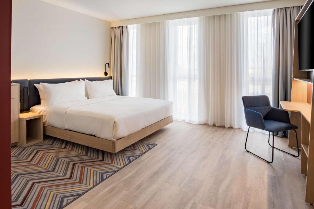 a bedroom with a bed and a desk and a chair at Hampton by Hilton Riga Airport in Riga