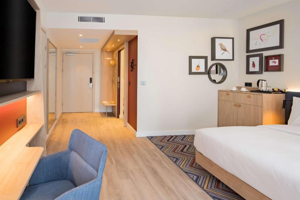 a hotel room with a bed and a blue chair at Hampton by Hilton Riga Airport in Riga