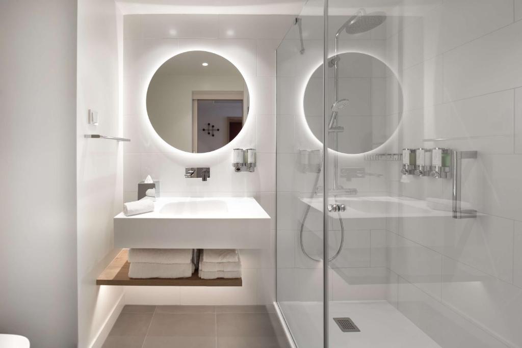 a white bathroom with a sink and a mirror at Hampton by Hilton Riga Airport in Riga