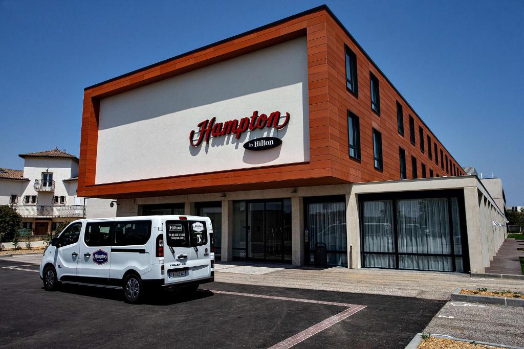 uma carrinha branca estacionada em frente a um edifício em Hampton By Hilton Toulouse Airport em Blagnac