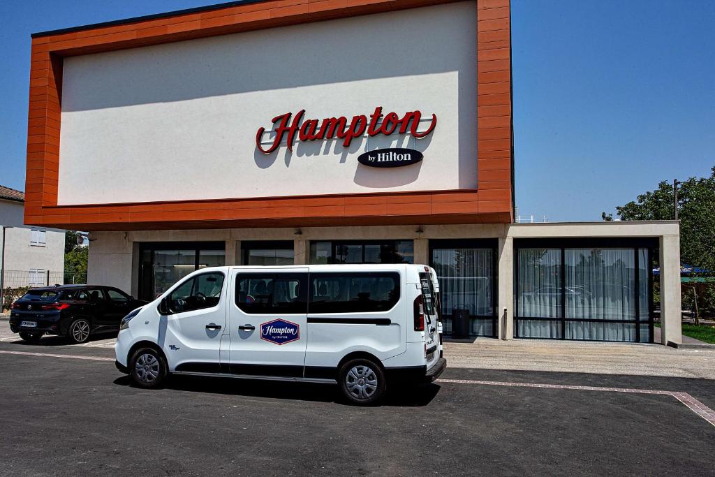 a white van parked in a parking lot in front of a pharmacy at Hampton By Hilton Toulouse Airport in Blagnac