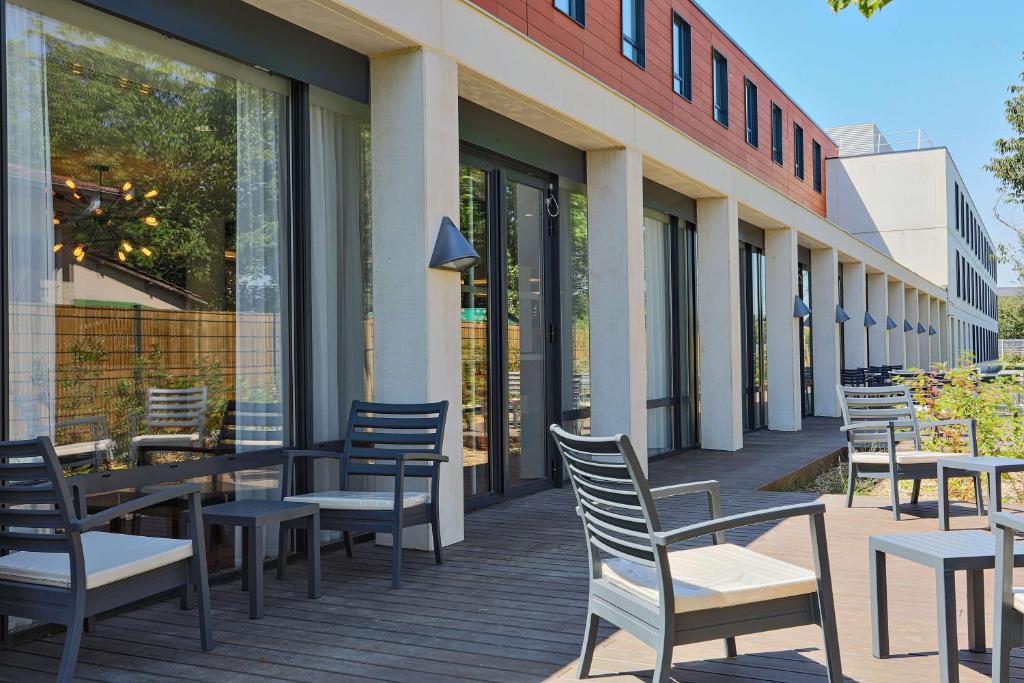 a row of chairs and tables outside of a building at Hampton By Hilton Toulouse Airport in Blagnac
