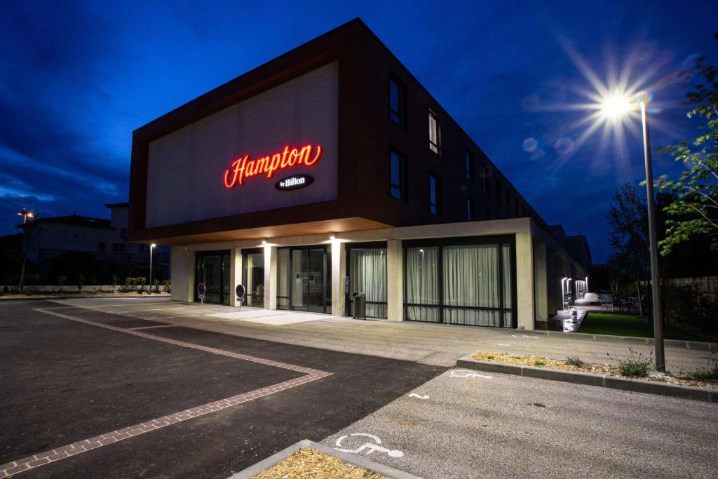 a building with a neon sign on the side of it at Hampton By Hilton Toulouse Airport in Blagnac