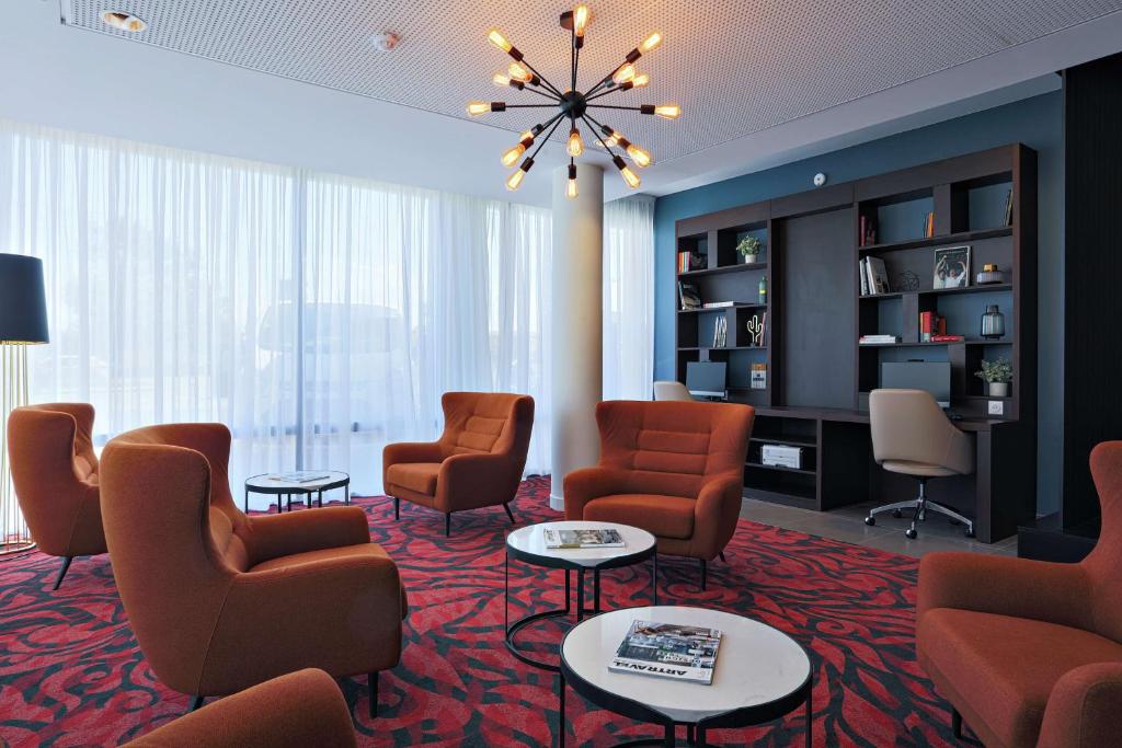 a waiting room with chairs and tables and a chandelier at Hampton By Hilton Toulouse Airport in Blagnac