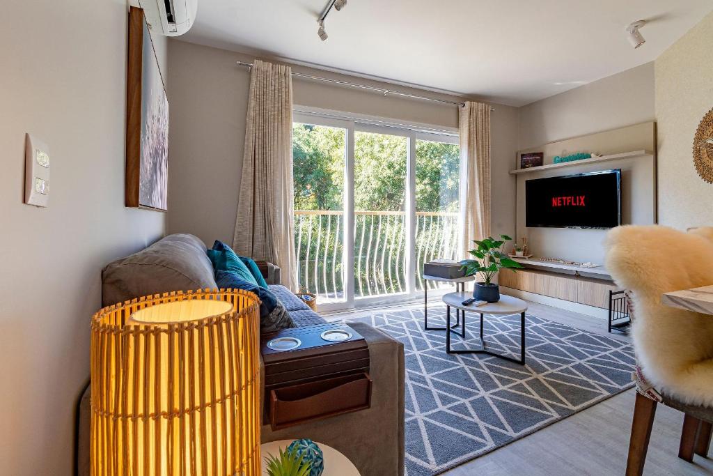a living room with a couch and a tv at Bem localizado - @stayhousetemporada in Canela