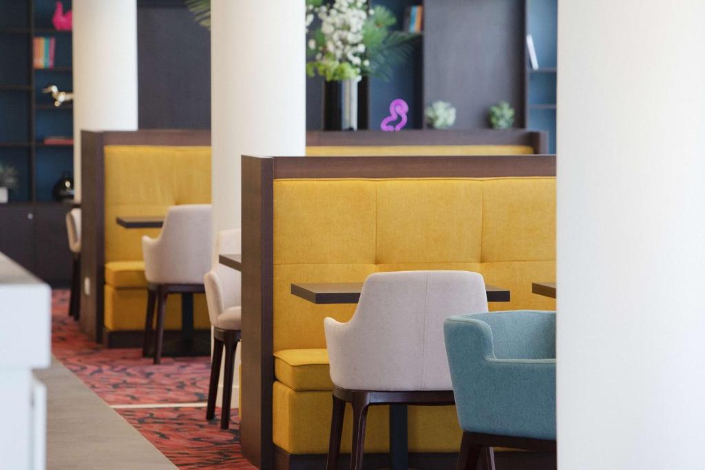 a row of chairs and tables in a waiting room at Hampton By Hilton Toulouse Airport in Blagnac