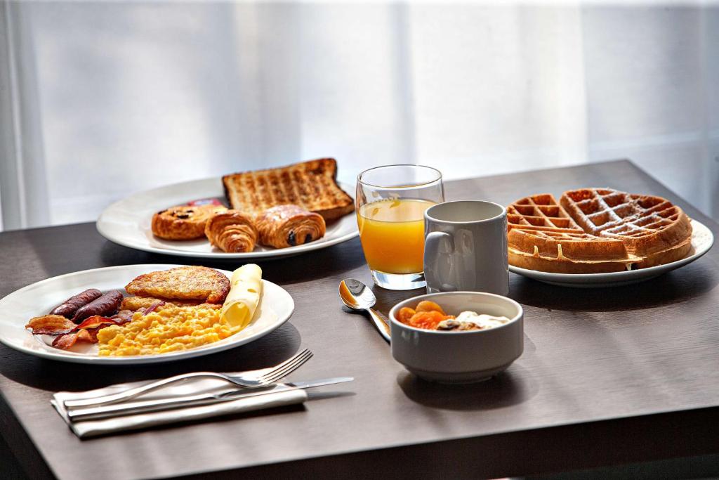 a table with two plates of breakfast foods and a glass of orange juice at Hampton By Hilton Toulouse Airport in Blagnac