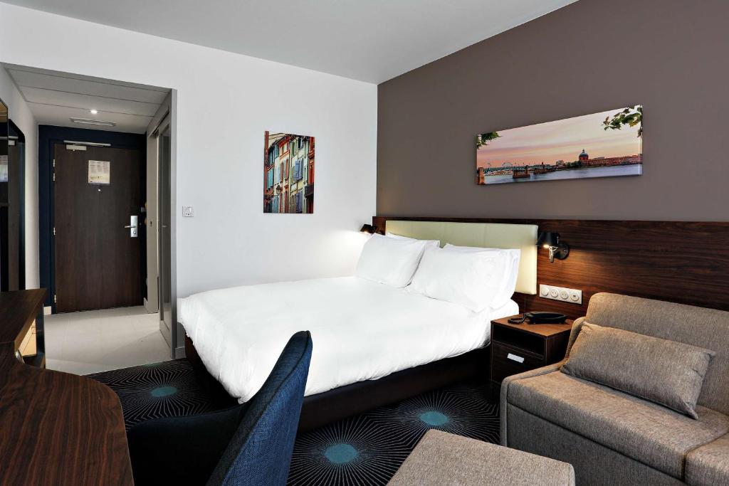 a hotel room with a bed and a couch at Hampton By Hilton Toulouse Airport in Blagnac