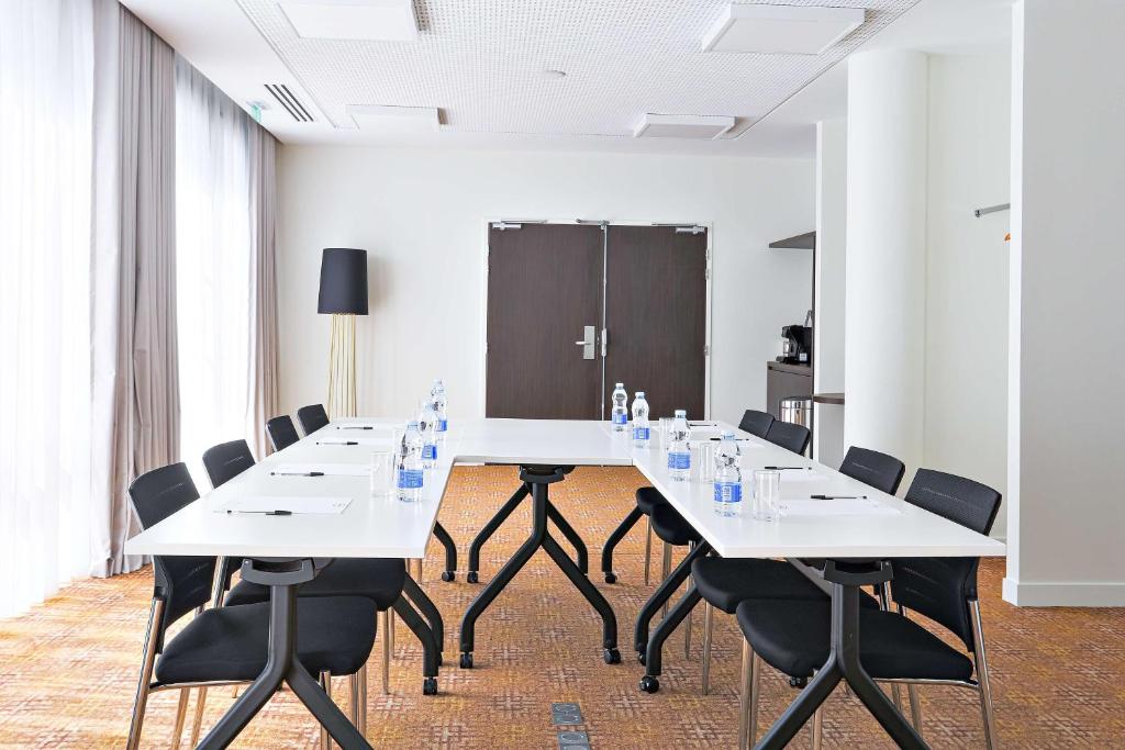 a conference room with white tables and black chairs at Hampton By Hilton Toulouse Airport in Blagnac