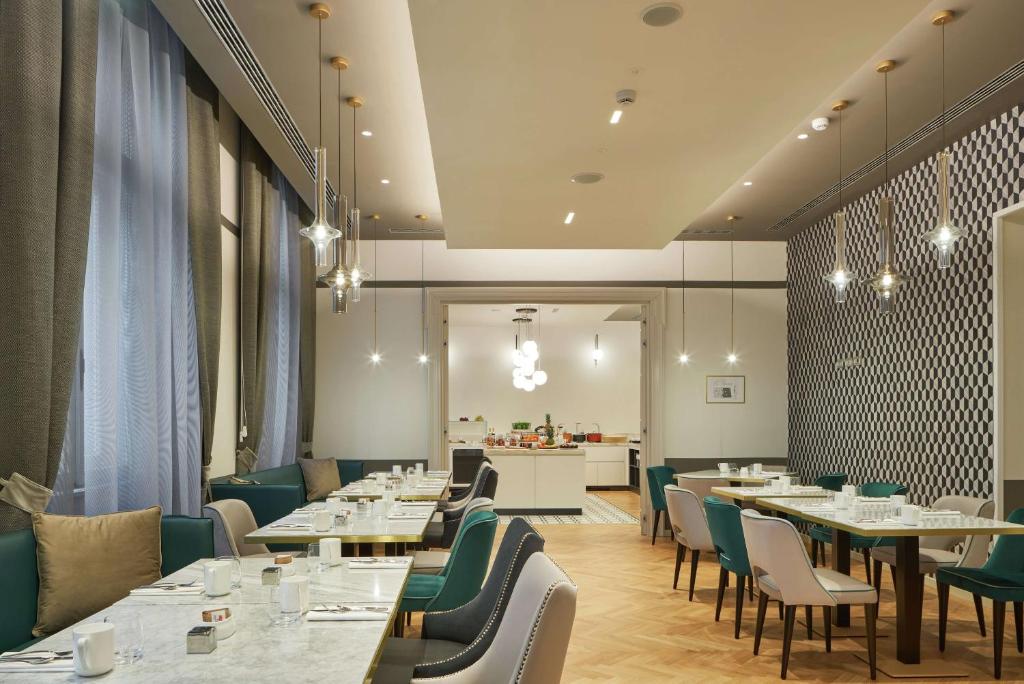 a restaurant with tables and chairs and a kitchen at DoubleTree By Hilton Trieste in Trieste