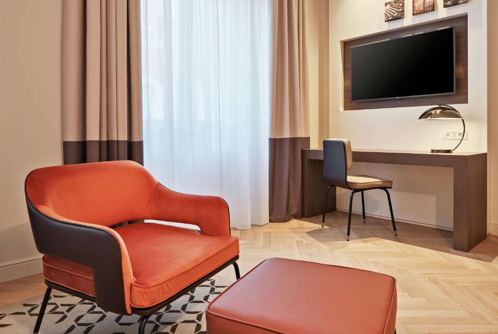 a living room with a chair and a television at DoubleTree By Hilton Trieste in Trieste