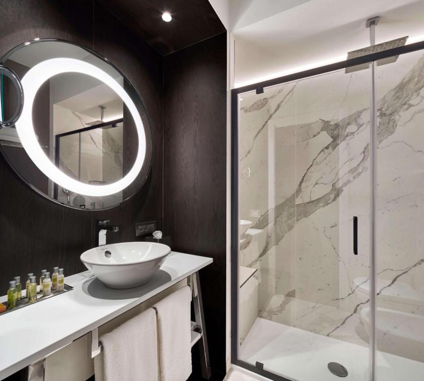 a bathroom with a sink and a shower with a mirror at DoubleTree By Hilton Trieste in Trieste