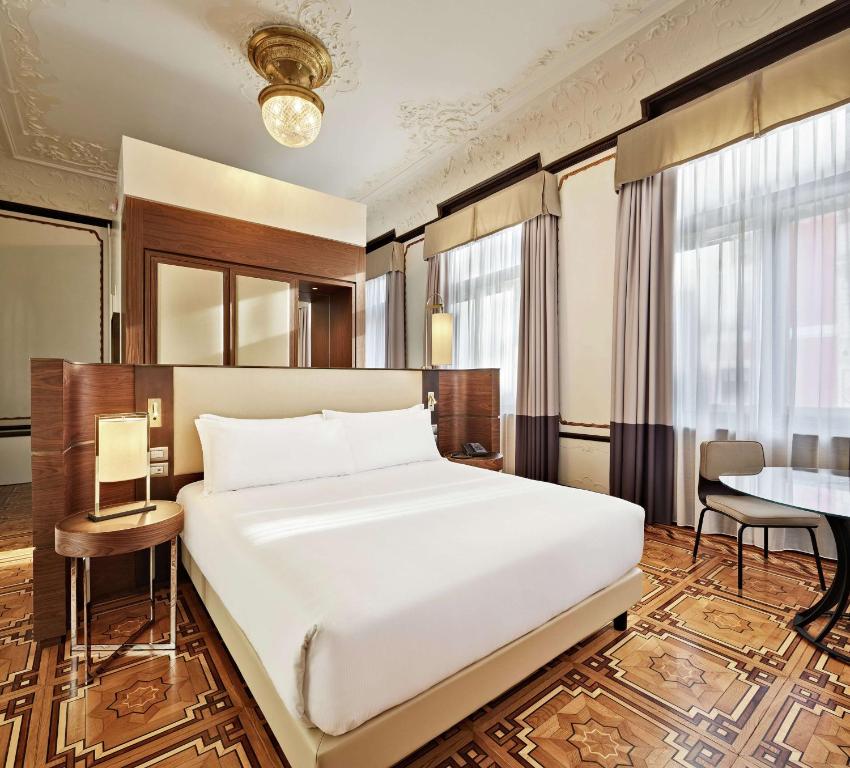 a bedroom with a large white bed and a desk at DoubleTree By Hilton Trieste in Trieste