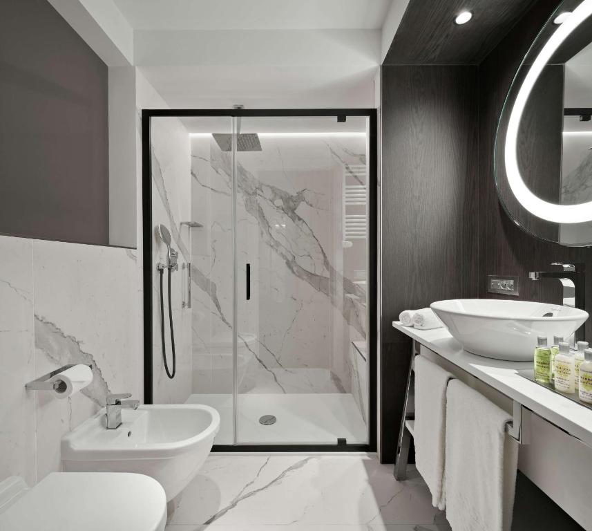 a bathroom with a shower and a toilet and a sink at DoubleTree By Hilton Trieste in Trieste