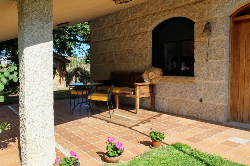 a patio with a table and chairs and a stone wall at Casa AsCampinas in Ourense
