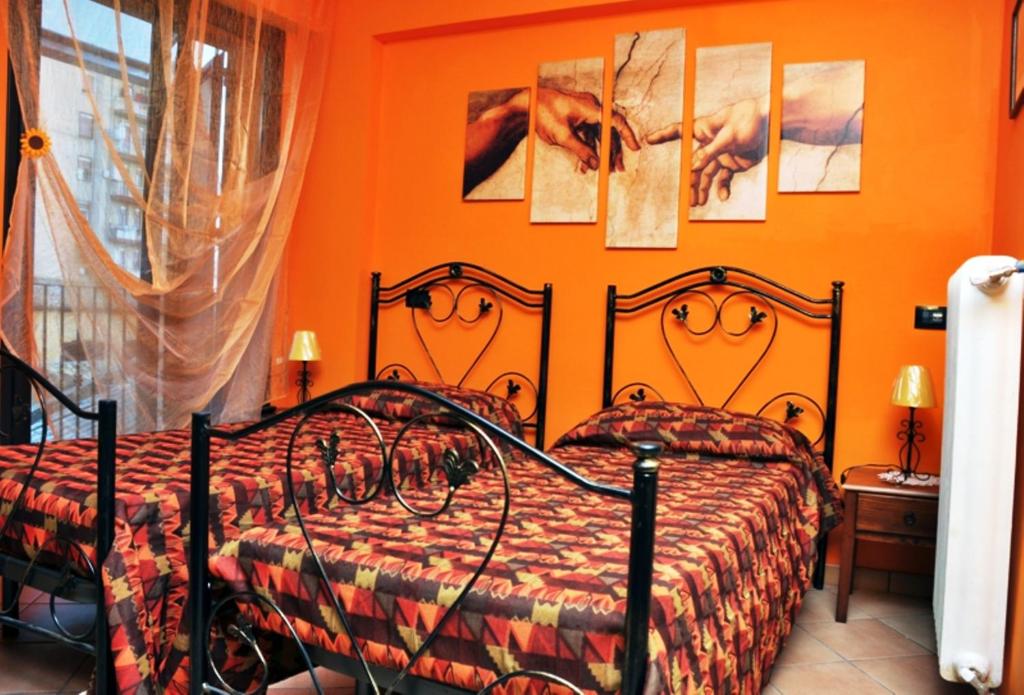 a bedroom with two beds with orange walls at Il Sole e La Luna in Agrigento