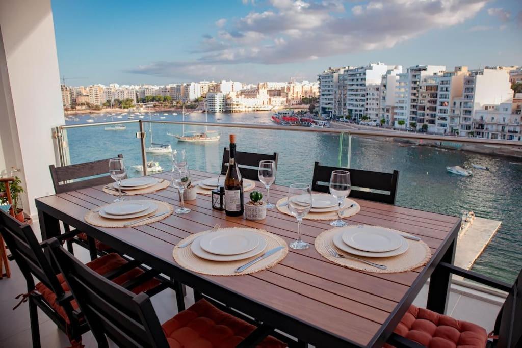- une table avec des verres à vin et une vue sur l'eau dans l'établissement Seafront Two Bedroom Apartment, à San Ġiljan