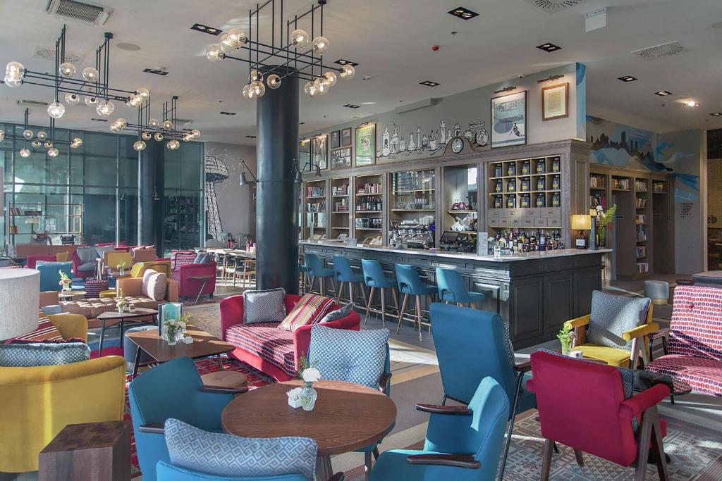 a restaurant with colorful chairs and a bar at Canopy by Hilton Zagreb City Centre in Zagreb