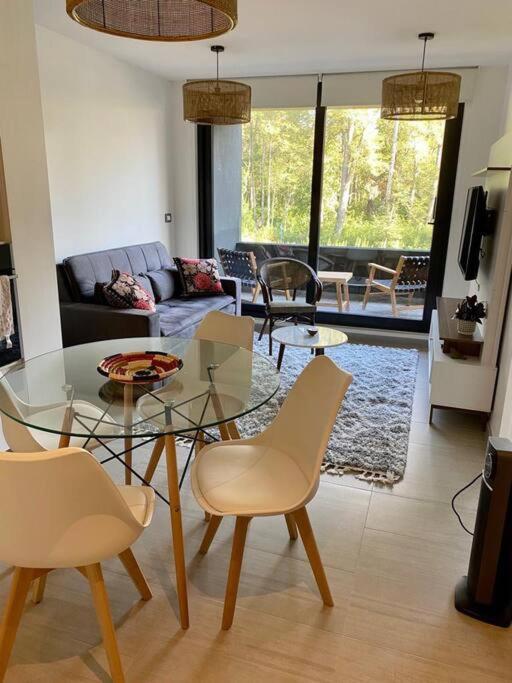 Una sala de estar con una mesa de cristal y sillas. en hermoso departamento 1 dormitorio en entorno natural, en Pucón