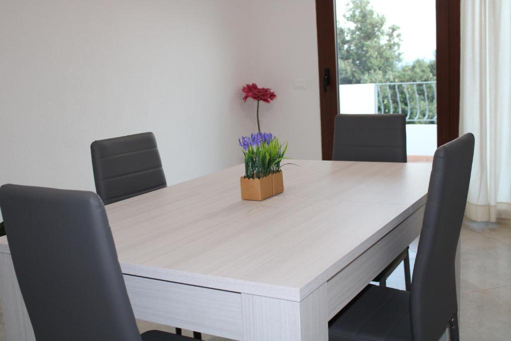 a white table with chairs and a vase of flowers on it at Casa Bel Panorama in Orosei