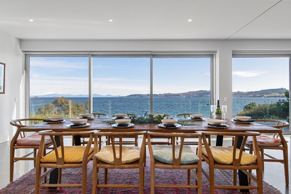 uma sala de jantar com mesa e cadeiras e uma grande janela em Linger Lakeside em Taupo