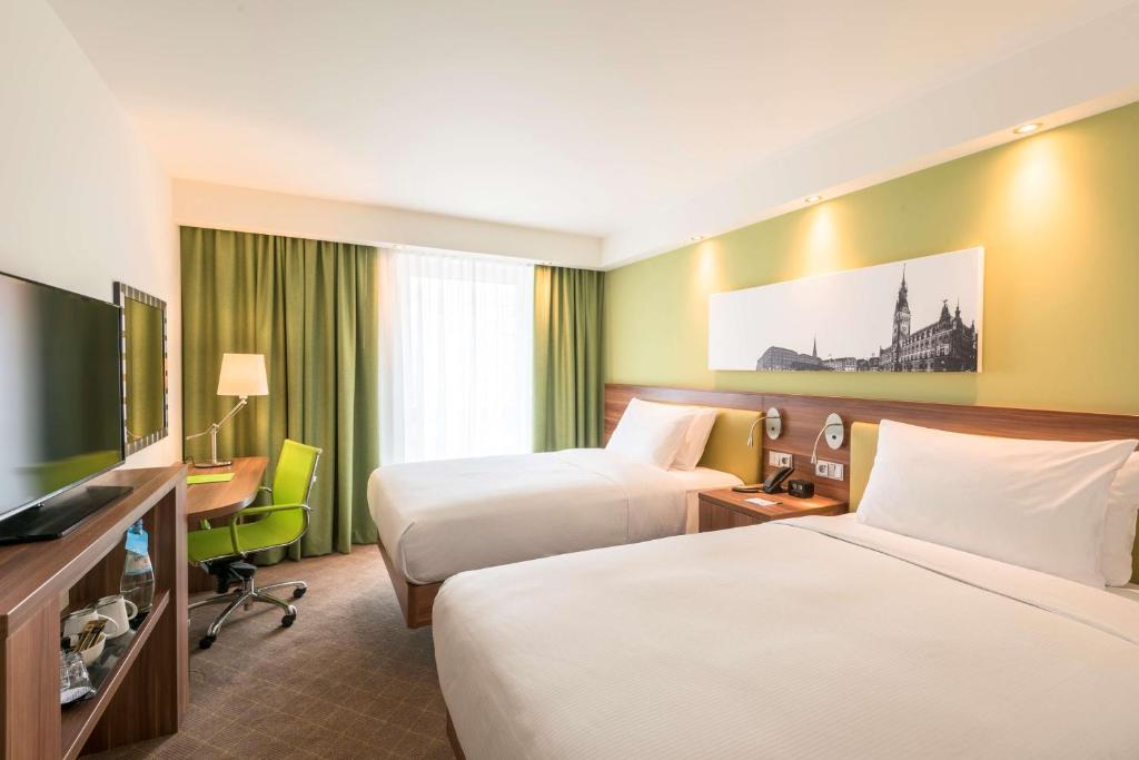 a hotel room with two beds and a television at Hampton By Hilton Hamburg City Centre in Hamburg