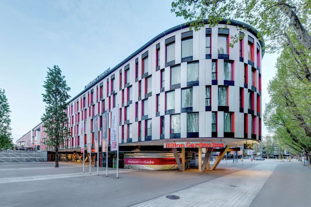 ein hohes Gebäude mit einer roten und weißen Fassade in der Unterkunft Hilton Garden Inn Stuttgart NeckarPark in Stuttgart