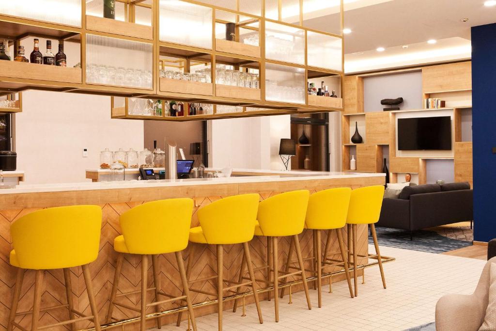 un bar con sedie gialle in una stanza di Hilton Garden Inn Munich Messe a Feldkirchen