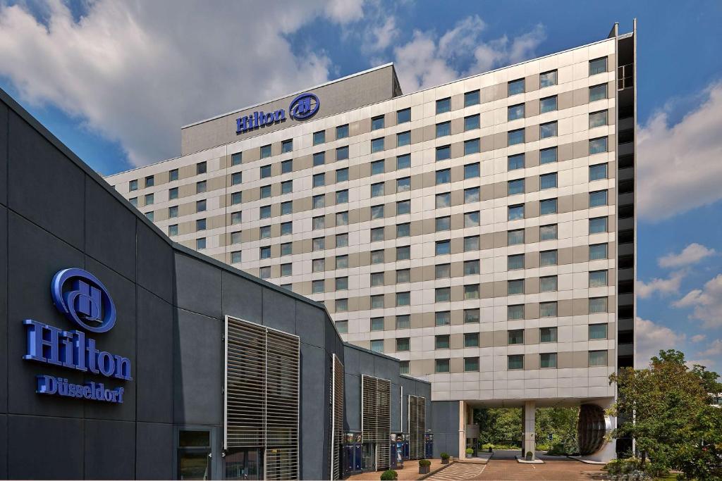 a high rise building with a blue hotel sign on it at Hilton Düsseldorf in Düsseldorf