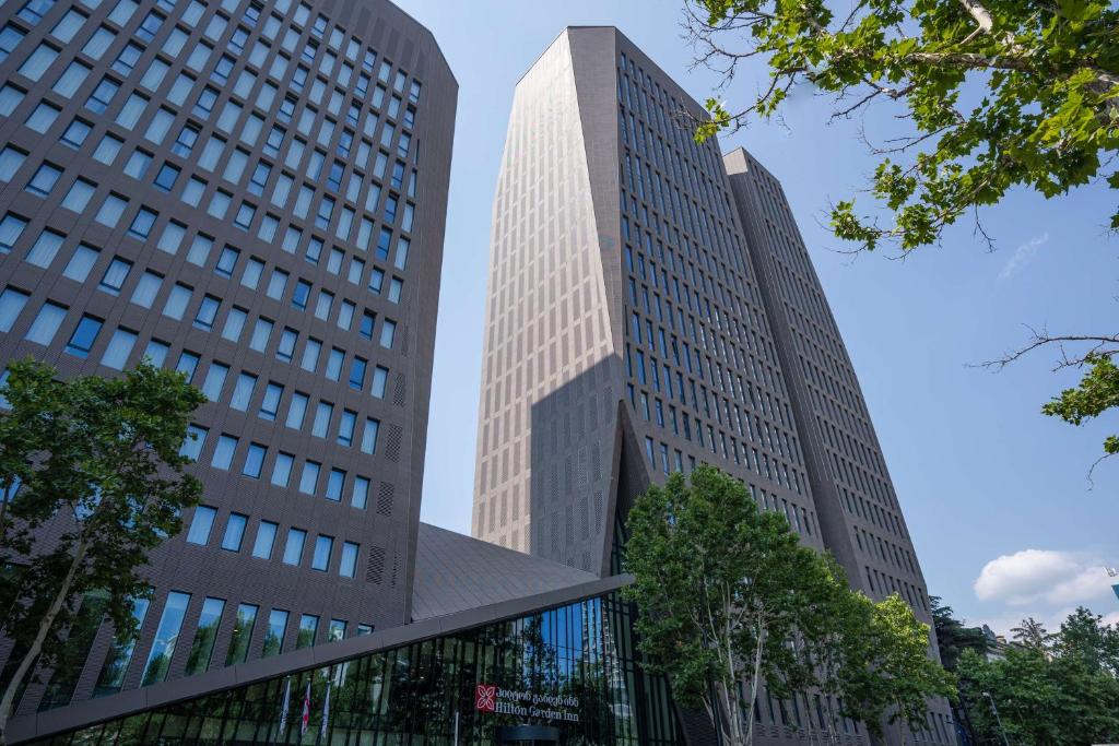 two tall buildings in a city with trees at Hilton Garden Inn Tbilisi Chavchavadze in Tbilisi City