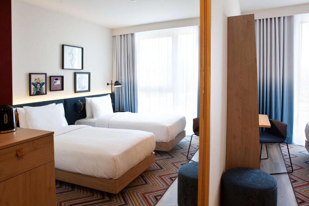 Una habitación de hotel con dos camas y una ventana. en Hampton by Hilton Munich Airport South, en Hallbergmoos