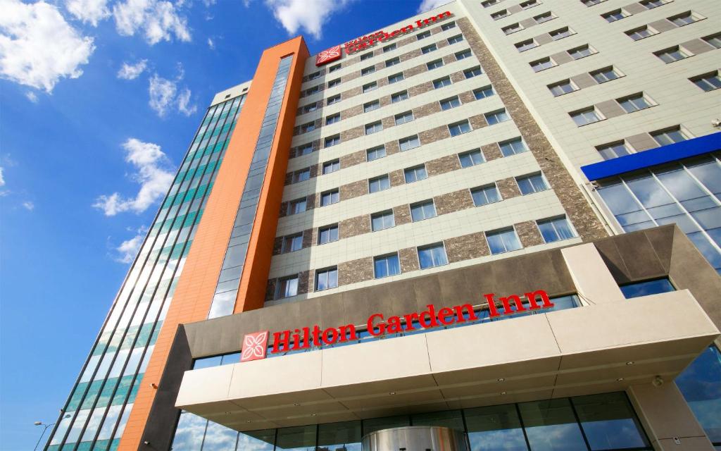 a tall building with a red sign on it at Hilton Garden Inn Volgograd in Volgograd