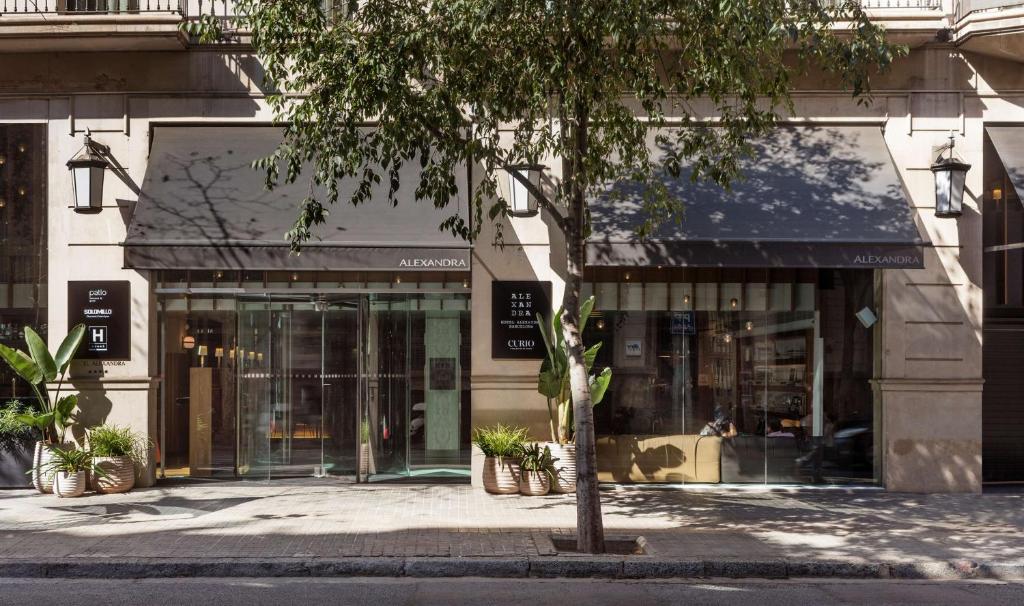 una tienda frente a un edificio con un árbol delante en Alexandra Barcelona Hotel, Curio Collection by Hilton, en Barcelona