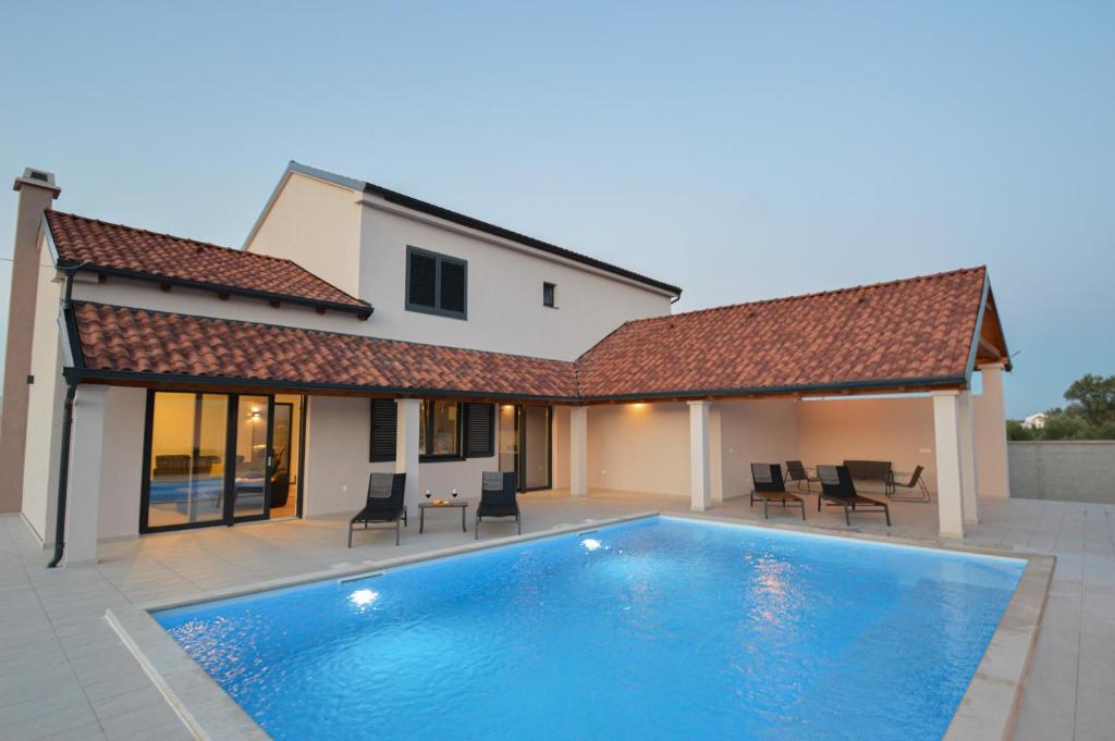 a swimming pool in front of a house at Villa DOKA in Donji Zemunik