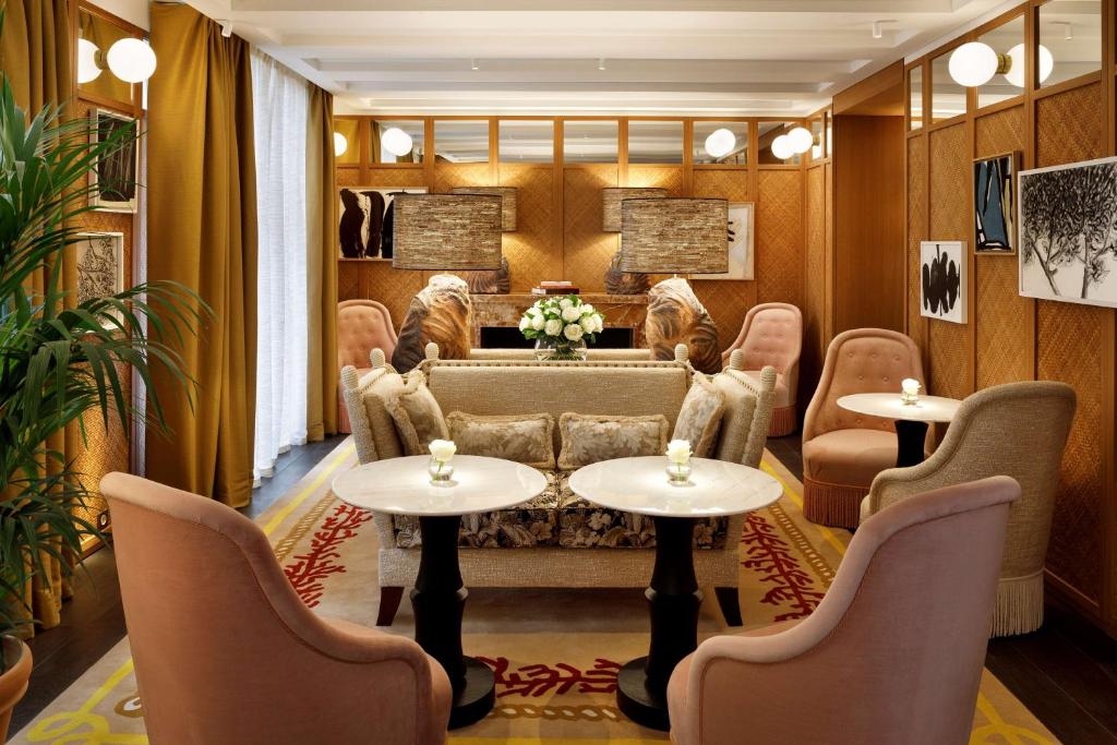 - une salle d'attente avec un canapé, 2 tables et des chaises dans l'établissement Le Belgrand Hotel Paris Champs Elysees, Tapestry By Hilton, à Paris