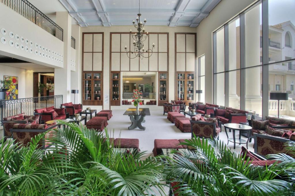 um átrio com sofás, mesas e plantas em Doubletree By Hilton La Torre Golf Resort em Roldán