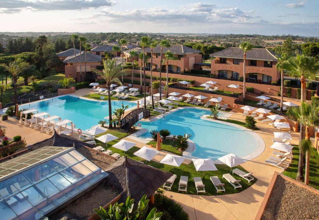 an aerial view of a resort swimming pool with lounge chairs at DoubleTree by Hilton Islantilla Beach Golf Resort in Islantilla