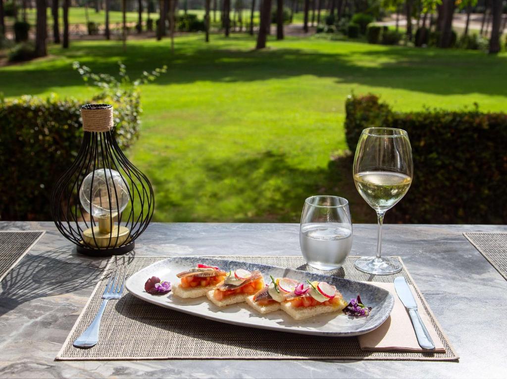 a plate of food on a table with wine glasses at DoubleTree by Hilton Islantilla Beach Golf Resort in Islantilla