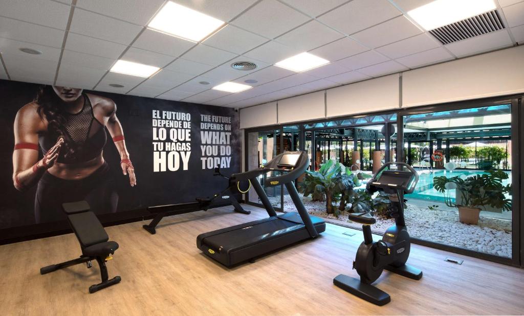 a gym with cardio equipment and a large poster on the wall at DoubleTree by Hilton Islantilla Beach Golf Resort in Islantilla