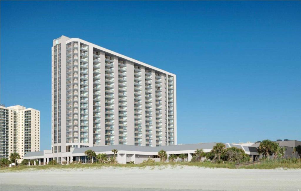 a large white building next to a beach at Embassy Suites by Hilton Myrtle Beach Oceanfront Resort in Myrtle Beach