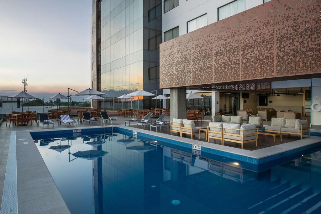 une piscine avec des chaises et des tables ainsi qu'un bâtiment dans l'établissement Doubletree By Hilton Celaya, à Celaya