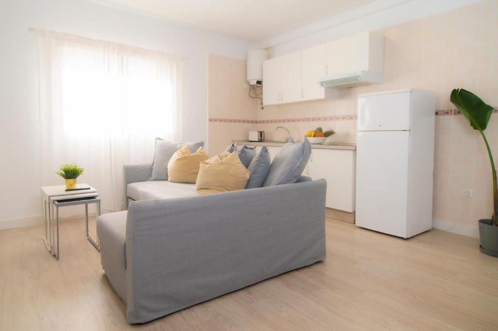 uma sala de estar com um sofá cinzento e uma cozinha em Alojamiento Guayarmina em La Restinga