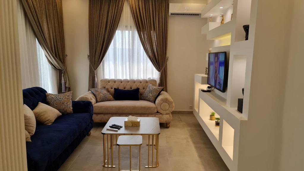 a living room with a blue couch and a tv at KBK Lodge in Abaga