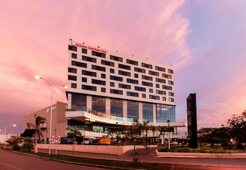 um edifício branco alto com muitas janelas em Hilton Garden Inn Merida em Mérida