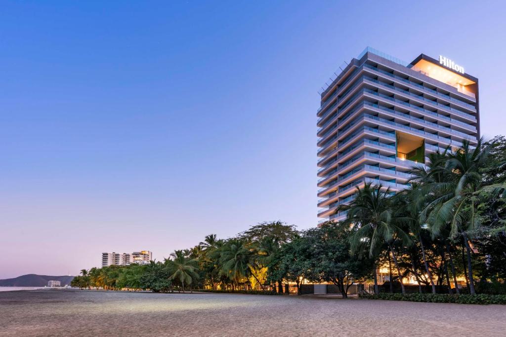 a tall building with palm trees in front of it at Hilton Santa Marta in Santa Marta